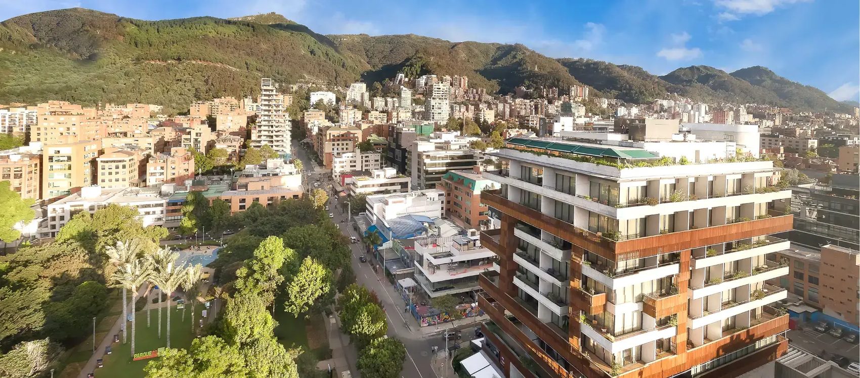 Panoramic view of Bogotá's Parque de la 93 district — modern mid-rise offices and apartments backed by the green Eastern Hills (Cerros Orientales)